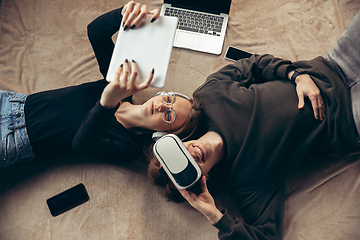 Image showing Attractive young couple using devices together, tablet, laptop, smartphone, headphones wireless. Gadgets and technologies connecting people all around the world. Top view