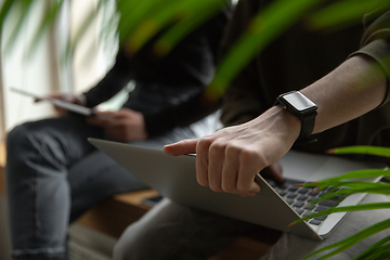 Image showing Close up of two people, couple using smartphone, laptop, smartwatch, education and business concept, communication during self-insulation