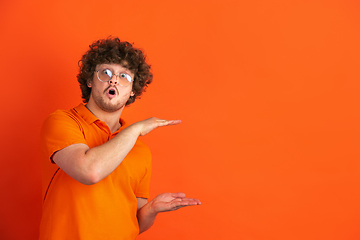 Image showing Caucasian young man\'s monochrome portrait on orange studio background