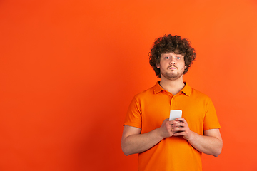 Image showing Caucasian young man\'s monochrome portrait on orange studio background