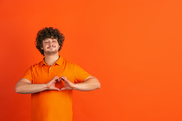 Image showing Caucasian young man\'s monochrome portrait on orange studio background