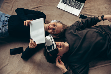 Image showing Attractive young couple using devices together, tablet, laptop, smartphone, headphones wireless. Gadgets and technologies connecting people all around the world