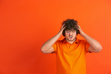 Image showing Caucasian young man\'s monochrome portrait on orange studio background