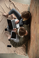 Image showing Attractive young couple using devices together, tablet, laptop, smartphone, headphones wireless. Gadgets and technologies connecting people all around the world. Top view