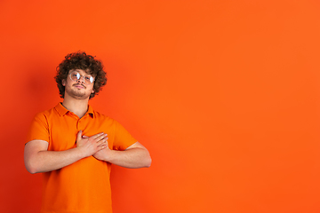 Image showing Caucasian young man\'s monochrome portrait on orange studio background