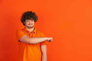 Image showing Caucasian young man\'s monochrome portrait on orange studio background