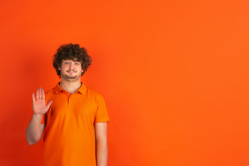 Image showing Caucasian young man\'s monochrome portrait on orange studio background