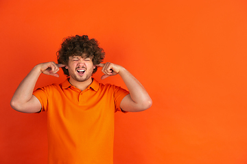 Image showing Caucasian young man\'s monochrome portrait on orange studio background