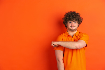 Image showing Caucasian young man\'s monochrome portrait on orange studio background