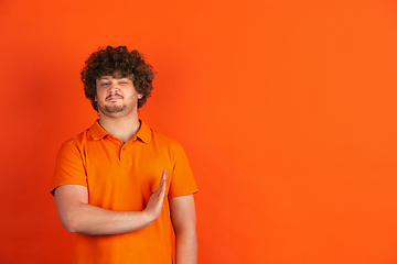 Image showing Caucasian young man\'s monochrome portrait on orange studio background