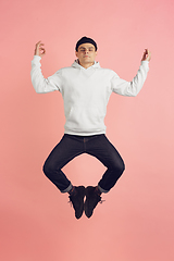 Image showing Caucasian young man\'s modern portrait on pink studio background in high jump