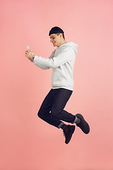 Image showing Caucasian young man\'s modern portrait on pink studio background in high jump