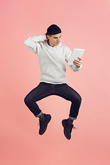 Image showing Caucasian young man\'s modern portrait on pink studio background in high jump