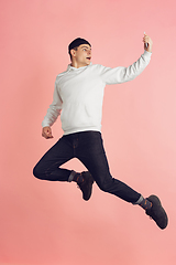 Image showing Caucasian young man\'s modern portrait on pink studio background in high jump