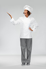 Image showing smiling female chef holding something on hand