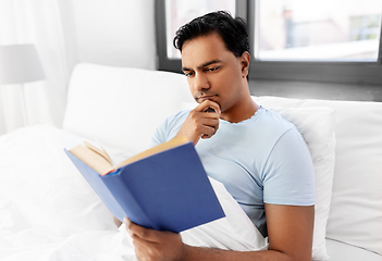 Image showing indian man reading book in bed at home