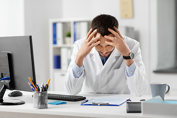 Image showing stressed male doctor with clipboard at hospital