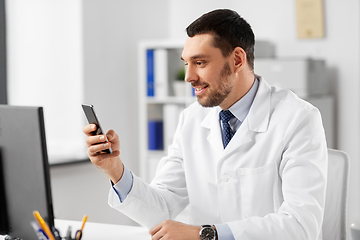 Image showing smiling male doctor with smartphone at hospital