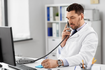 Image showing male doctor calling on desk phone at hospital