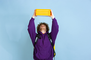 Image showing Contacless delivery service during quarantine. Man delivers food and shopping bags during insulation. Emotions of deliveryman isolated on blue background.