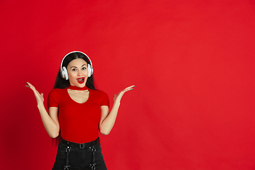 Image showing Caucasian young woman\'s monochrome portrait on red studio background, emotional and expressive