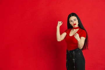 Image showing Caucasian young woman\'s monochrome portrait on red studio background, emotional and expressive