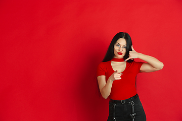 Image showing Caucasian young woman\'s monochrome portrait on red studio background, emotional and expressive