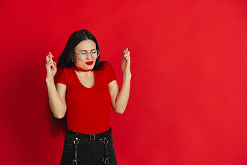 Image showing Caucasian young woman\'s monochrome portrait on red studio background, emotional and expressive