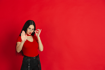 Image showing Caucasian young woman\'s monochrome portrait on red studio background, emotional and expressive