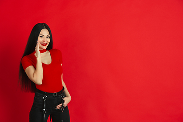 Image showing Caucasian young woman\'s monochrome portrait on red studio background, emotional and expressive