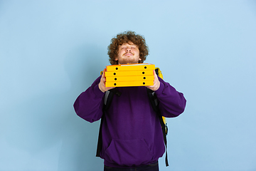 Image showing Contacless delivery service during quarantine. Man delivers food and shopping bags during insulation. Emotions of deliveryman isolated on blue background.