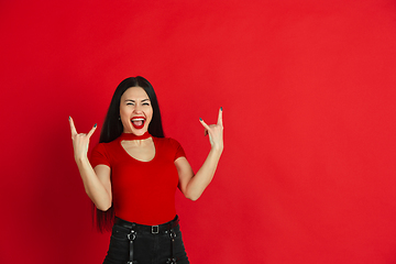 Image showing Caucasian young woman\'s monochrome portrait on red studio background, emotional and expressive