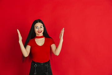 Image showing Caucasian young woman\'s monochrome portrait on red studio background, emotional and expressive