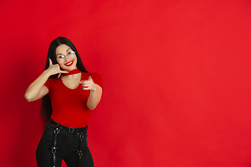 Image showing Caucasian young woman\'s monochrome portrait on red studio background, emotional and expressive