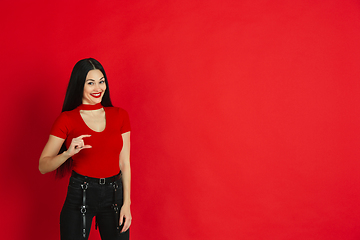 Image showing Caucasian young woman\'s monochrome portrait on red studio background, emotional and expressive