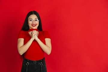 Image showing Caucasian young woman\'s monochrome portrait on red studio background, emotional and expressive