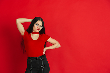 Image showing Caucasian young woman\'s monochrome portrait on red studio background, emotional and expressive