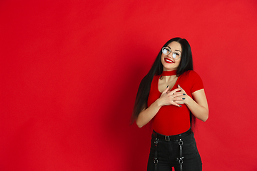 Image showing Caucasian young woman\'s monochrome portrait on red studio background, emotional and expressive