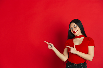 Image showing Caucasian young woman\'s monochrome portrait on red studio background, emotional and expressive