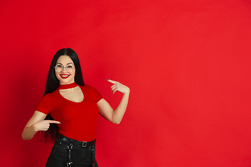 Image showing Caucasian young woman\'s monochrome portrait on red studio background, emotional and expressive