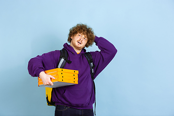 Image showing Contacless delivery service during quarantine. Man delivers food and shopping bags during insulation. Emotions of deliveryman isolated on blue background.