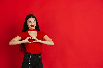 Image showing Caucasian young woman\'s monochrome portrait on red studio background, emotional and expressive