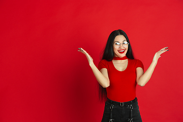 Image showing Caucasian young woman\'s monochrome portrait on red studio background, emotional and expressive