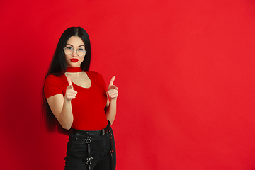 Image showing Caucasian young woman\'s monochrome portrait on red studio background, emotional and expressive