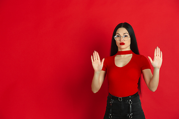 Image showing Caucasian young woman\'s monochrome portrait on red studio background, emotional and expressive