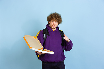 Image showing Contacless delivery service during quarantine. Man delivers food and shopping bags during insulation. Emotions of deliveryman isolated on blue background.