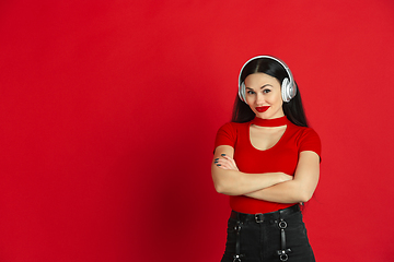 Image showing Caucasian young woman\'s monochrome portrait on red studio background, emotional and expressive