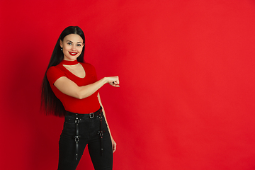 Image showing Caucasian young woman\'s monochrome portrait on red studio background, emotional and expressive