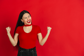 Image showing Caucasian young woman\'s monochrome portrait on red studio background, emotional and expressive