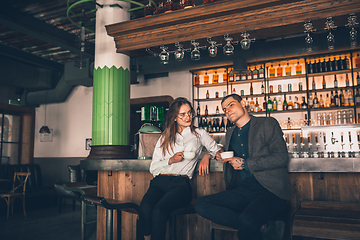 Image showing Cheerful man and woman talking, enjoying a coffee at the coffee shop, cafe, bar